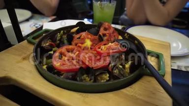 传统的西班牙海鲜饭，锅中有海鲜和蔬菜。